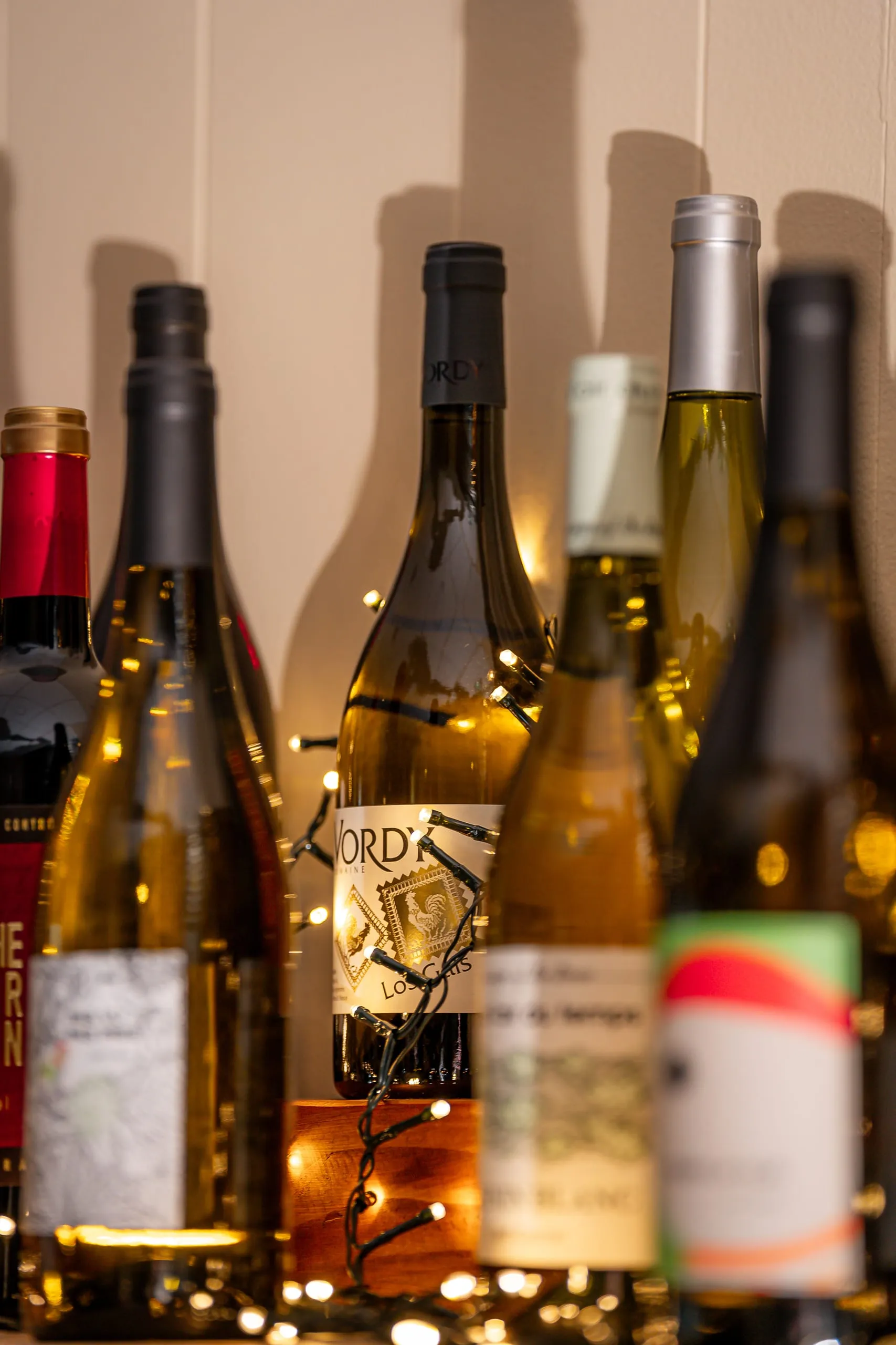 Bouteilles de vin présentées avec des guirlandes lumineuses