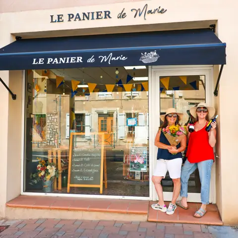 Devanture du Panier de Marie avec son enseigne, son store bleu et deux femmes devant l’entrée
