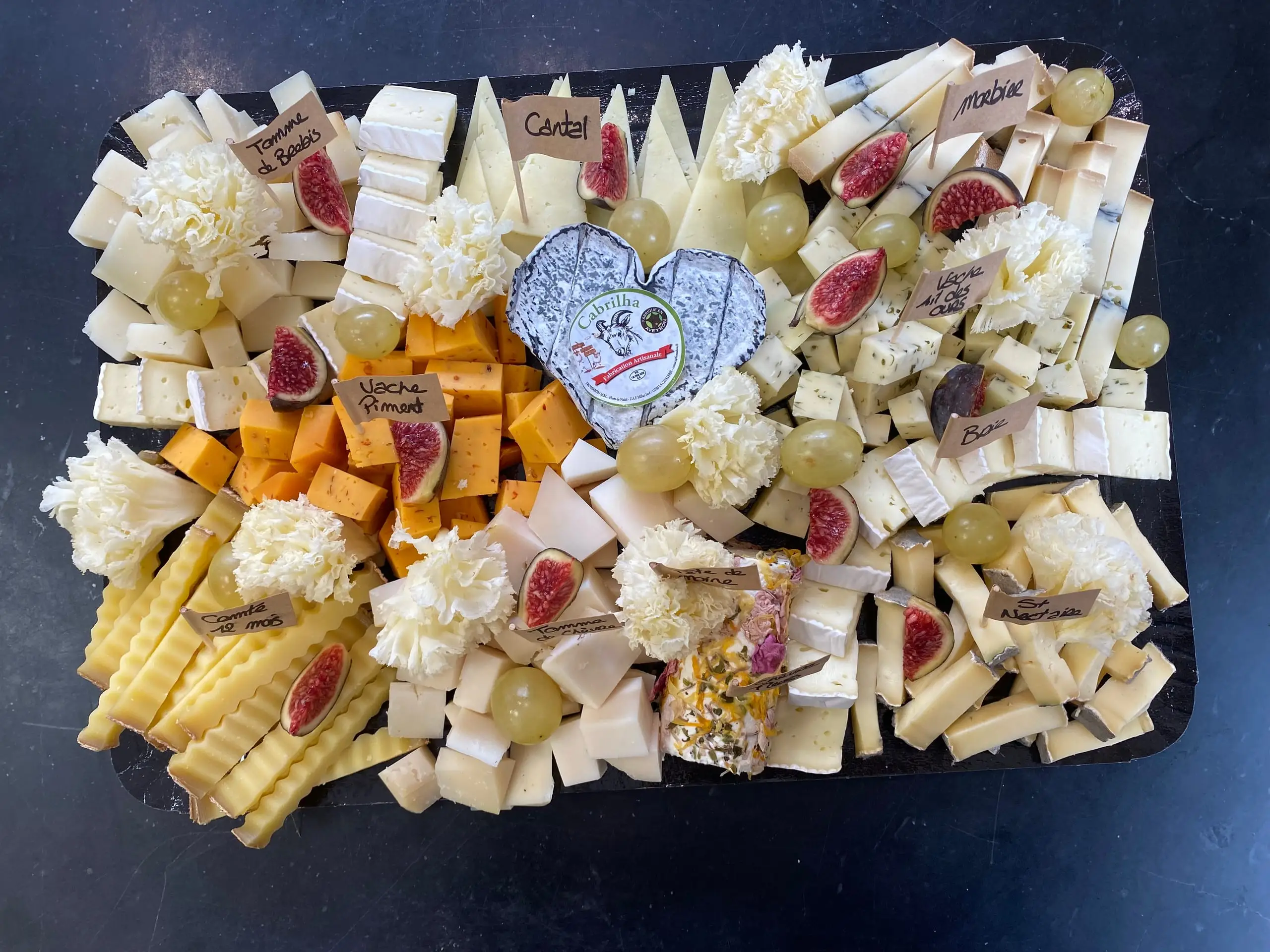 Plateau de fromages variés garni de figues, raisins et fleurs de fromage