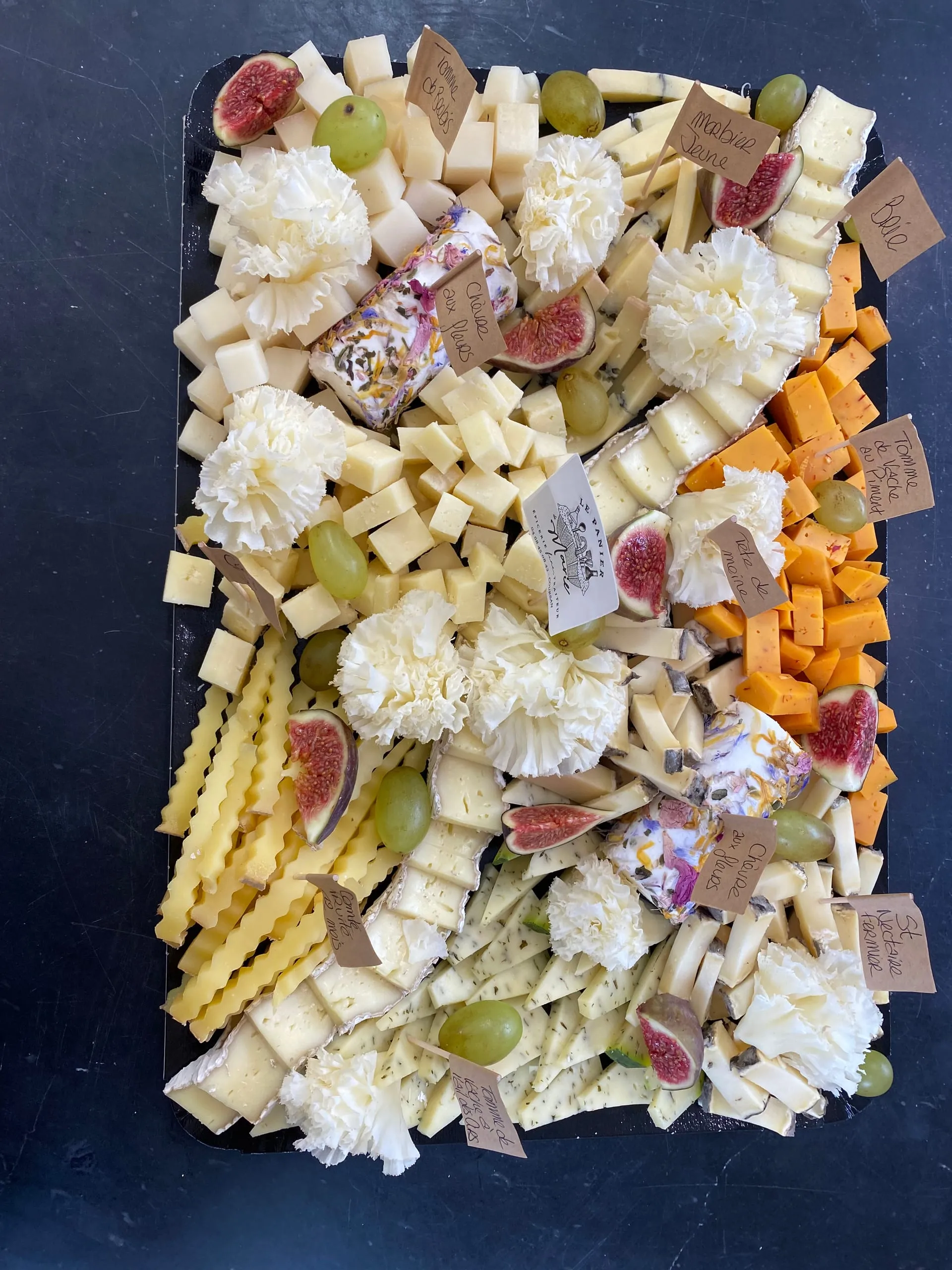 Grand plateau de fromages variés accompagné de raisins et de figues