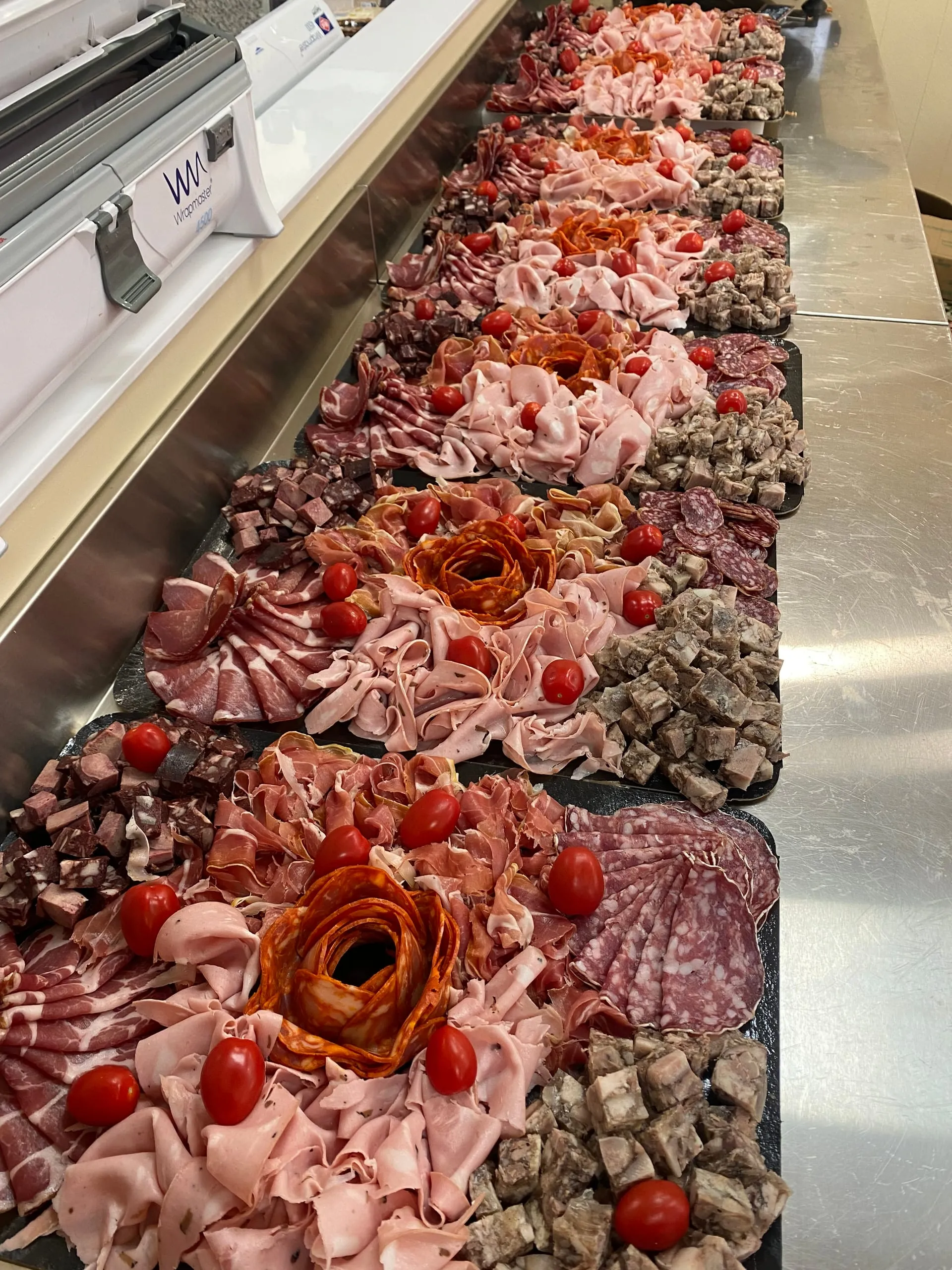 Plusieurs plateaux de charcuteries garnis de jambons, de saucissons et de tomates