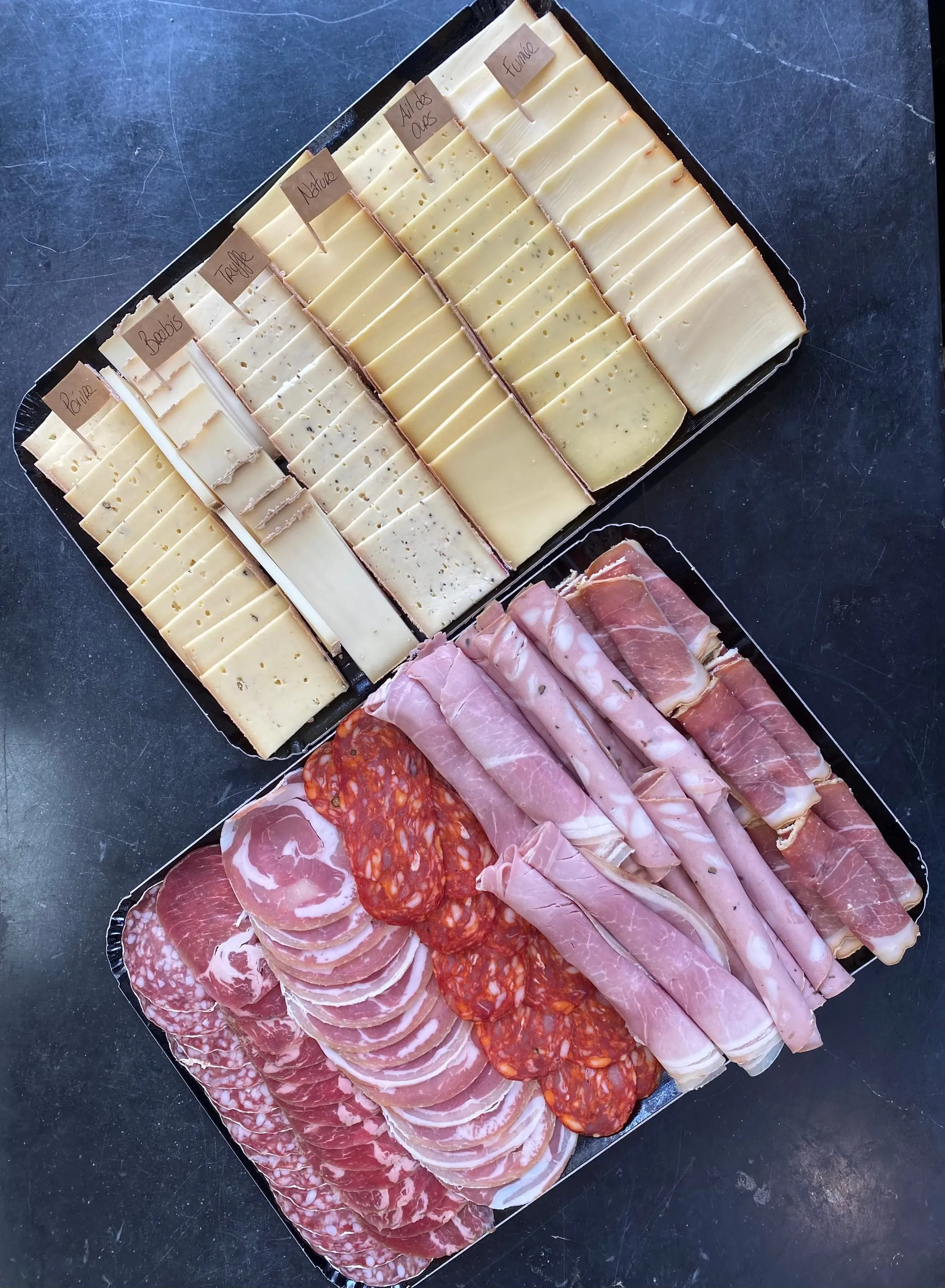 Deux plateaux assortis de fromages tranchés et de charcuteries