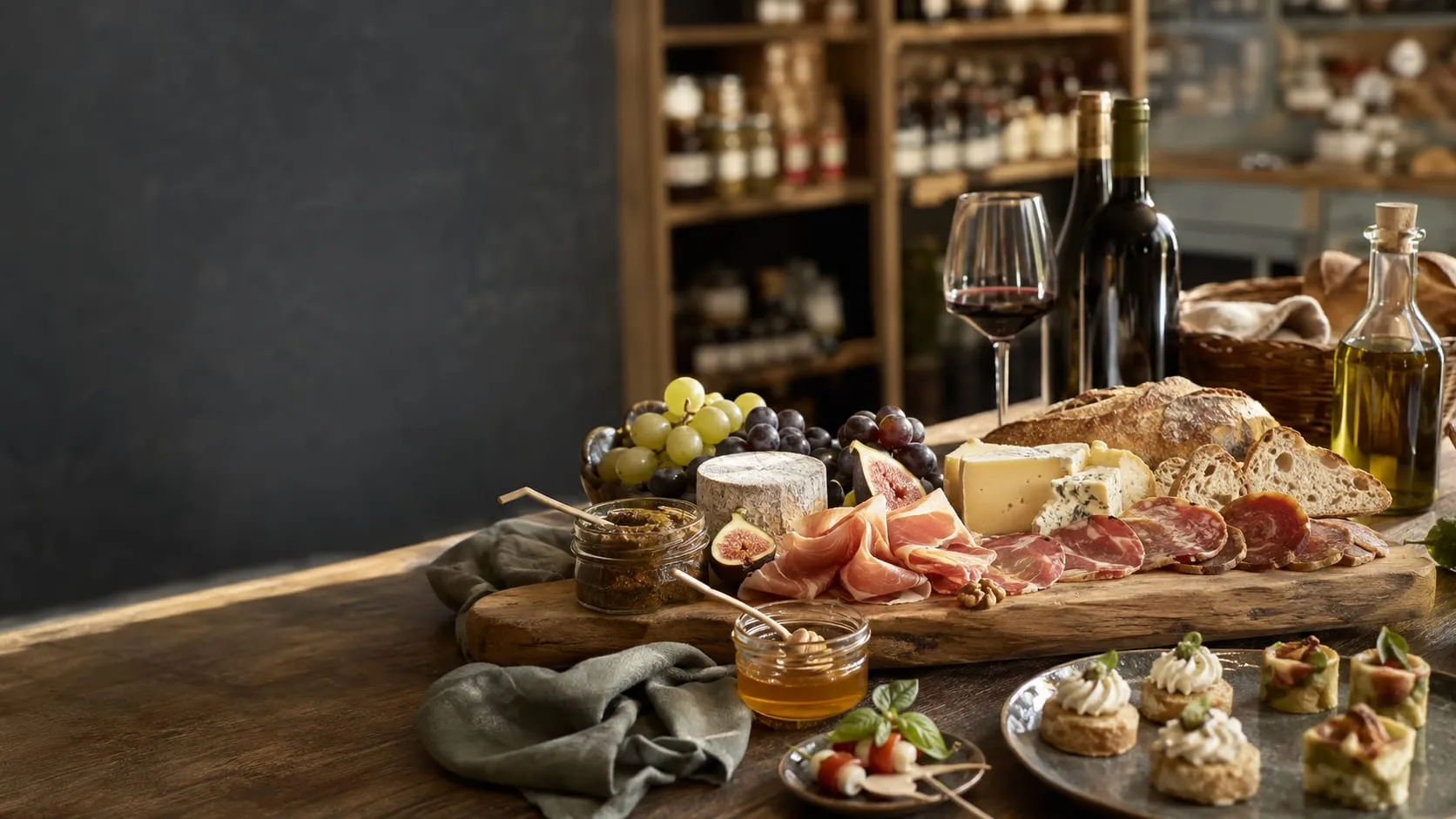 Table garnie de charcuteries, fromages, pains, raisins, figues et bouchées apéritives avec du vin et de l’huile d’olive